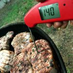 Pork chops on the grill checking internal temperature with Thermoworks Thermapen MK4.